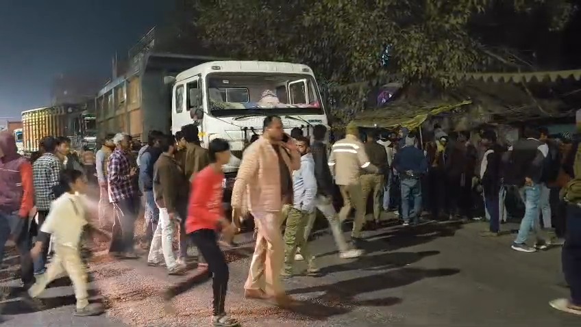 उत्तर प्रदेश के हमीरपुर में एनएच 34 पर हुए सड़क हादसे में क्षतिग्रस्त ट्रक और प्रदर्शन करती भीड़।