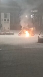 उत्तर प्रदेश के हमीरपुर में सुमेरपुर पेट्रोल पंप पर जलती हुई मोटरसाइकिल और आग बुझाते हुए कर्मचारी।